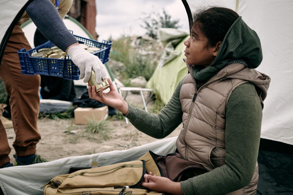 Giving Canned Food To Refugee Girl